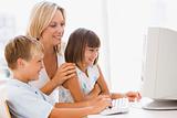 Woman and two young children in home office with computer smilin