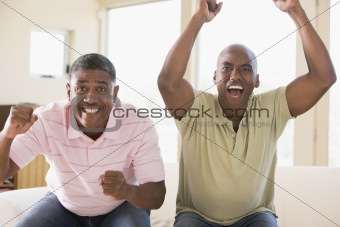 Two men in living room cheering and smiling
