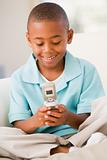 Young boy in living room using cellular phone and smiling