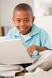 Young boy in living room with laptop smiling