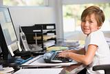 Young boy in home office with computer smiling