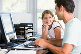 Man and young girl in home office with computer smiling