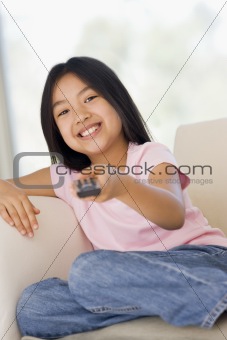 Young girl in living room with remote control smiling