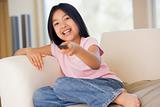 Young girl in living room with remote control smiling