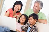 Couple with two young children in living room with laptop smilin
