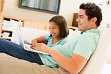 Man with young girl in living room with laptop smiling
