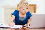 Young girl with laptop doing homework in dining room