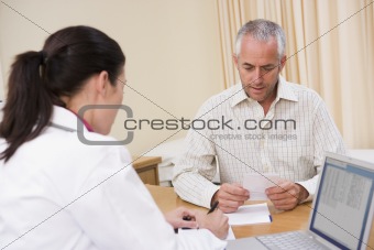 Doctor with laptop and man in doctor's office