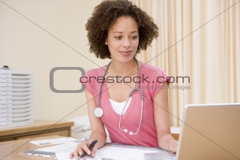 Doctor using laptop in doctor's office smiling