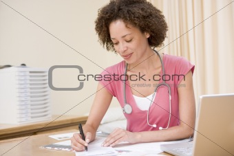 Doctor with laptop writing in doctor's office