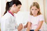 Doctor giving needle to young girl in exam room