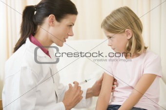 Doctor giving needle to young girl in exam room