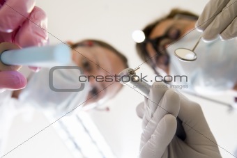 Dentist and assistant holding pick and mirror