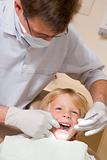 Dentist in exam room with young boy in chair