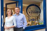 Couple standing at front entrance of optometrists smiling