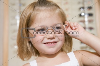 Young girl trying on eyeglasses at optometrists smiling
