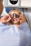 Optometrist in exam room with young girl in chair smiling