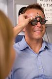 Optometrist in exam room with man in chair smiling