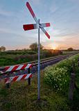 railway tracks with pastel sunset and traffic sign in a rural scene