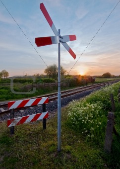 railway tracks with pastel sunset and traffic sign in a rural scene