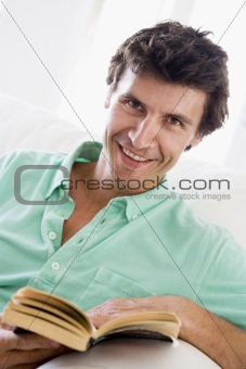 Man reading book in living room smiling