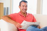 Man reading newspaper in living room smiling
