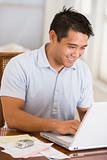 Man in dining room using laptop and smiling