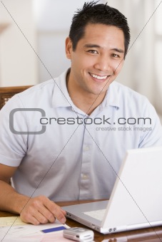 Man in dining room using laptop smiling