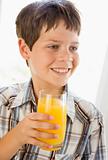 Young boy indoors drinking orange juice smiling