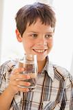Young boy indoors drinking water smiling