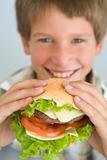 Young boy eating cheeseburger smiling