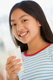 Young girl indoors drinking milk smiling