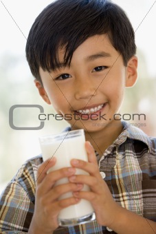 Young boy indoors drinking milk smiling