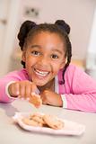 Young girl in kitchen eating cookies smiling
