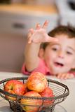 Young boy in kitchen getting apple off counter
