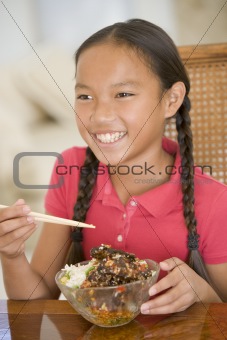Young girl in dining room eating chinese food smiling