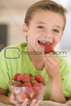 Young boy eating strawberries in living room smiling