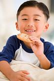 Young boy eating cookie in living room smiling