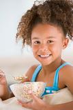 Young girl eating cereal in living room smiling