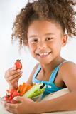 Young girl eating bowl of vegetables in living room smiling