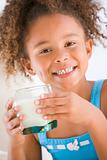 Young girl indoors drinking milk smiling