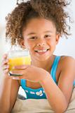 Young girl drinking orange juice in living room smiling