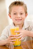 Young boy indoors with orange juice smiling