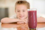Young boy indoors with focus on juice glass