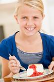 Young girl indoors eating cheesecake smiling