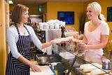 Woman standing at counter in restaurant serving customer and smi