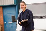 Deliveryperson standing with van writing in clipboard smiling