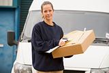 Deliveryperson standing with van with clipboard and box