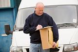 Deliveryperson standing with van writing in clipboard holding bo