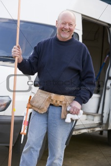 Plumber standing with van smiling